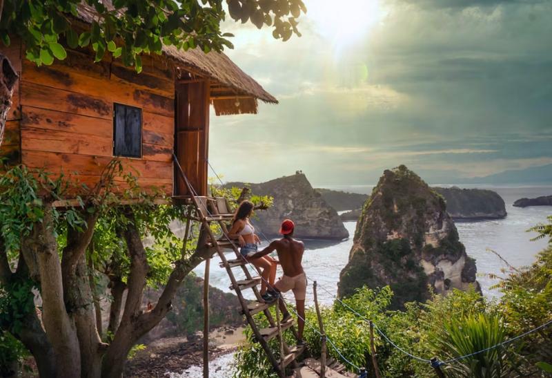 Pár na schodoch dreveného domu s výhľadom na more.