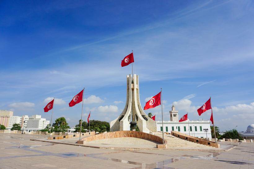 Námestie s budovami v meste Tunis s červenými vlajkami.