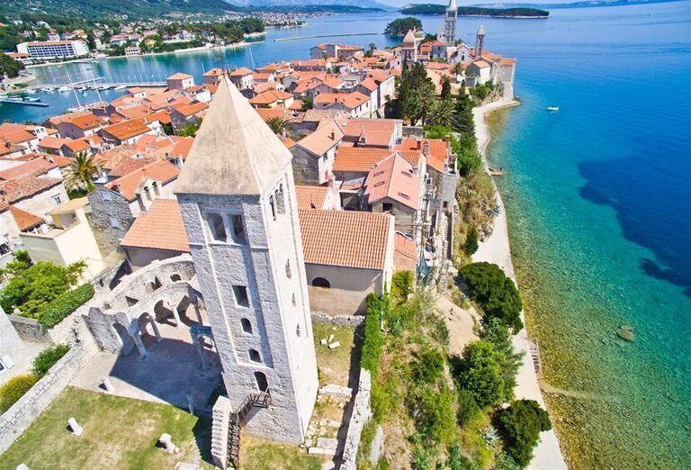 Kamenná veža, domy s červenými strechami a tyrkysové more v Chorvátsku.