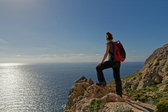 Žena s ruksakom na túre po útesoch s panoramatickým výhľadom na Egejské more na ostrove Kos, Grécko