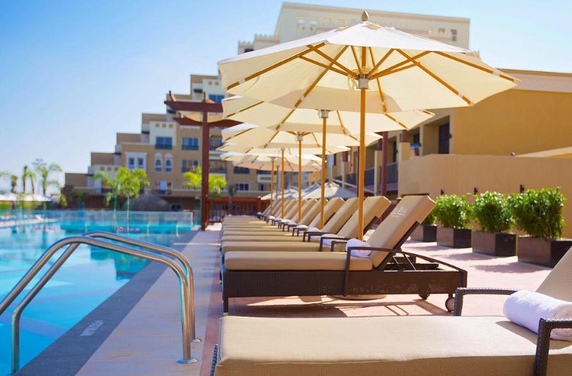 Hotelový bazén a lehátka. Rixos Bab Al Bahr. SAE.