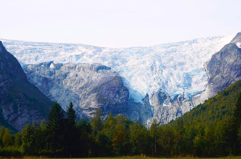 Ľadový splaz na skalnom masíve a zelená hora v Jostedalsbreen. Nórsko.
