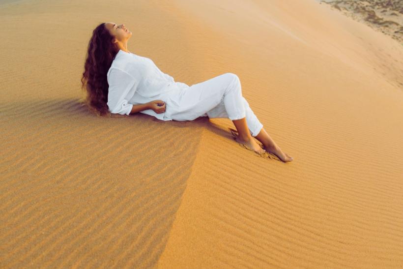 žena v bielom relaxuje na marockej púšti