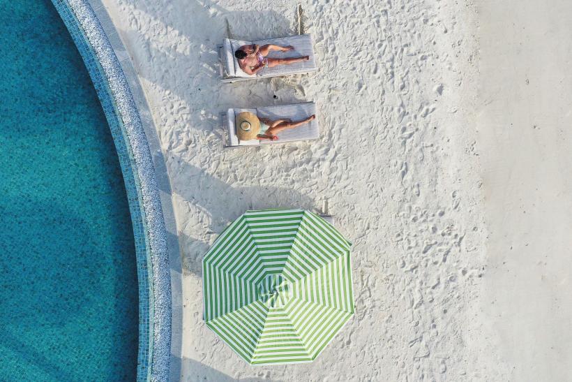 pohľad z výšky na oddychujúci párik na pláži hotela Le Meridien, Maldivy