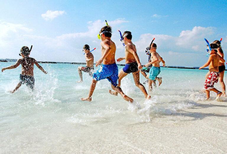 Deti so šnorchlom bežiace do vody. Maldivy