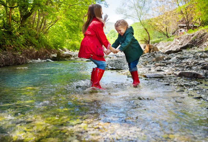 Dve deti v čižmách vo vode v prírode.