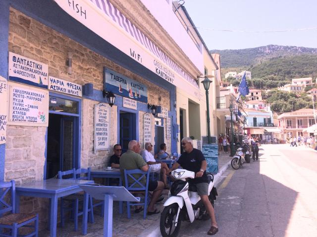 Grécka taverna, sediaci muži a prístav na ostrove Ithaka.