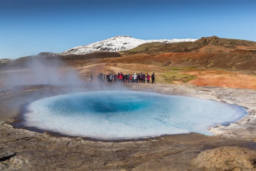 Skupina ľudí pozoruje horúce modré jazero. Island