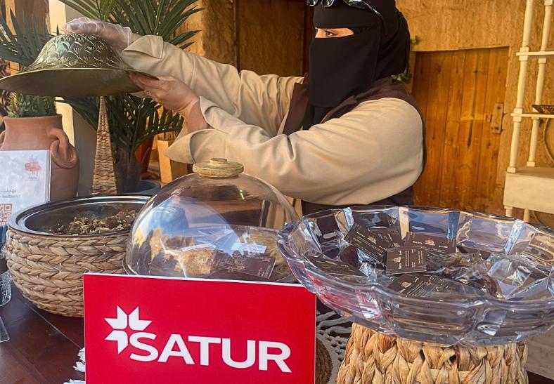 Saudská žena ponúka návštevníkov sušienkami, datľami a kávou. KSA