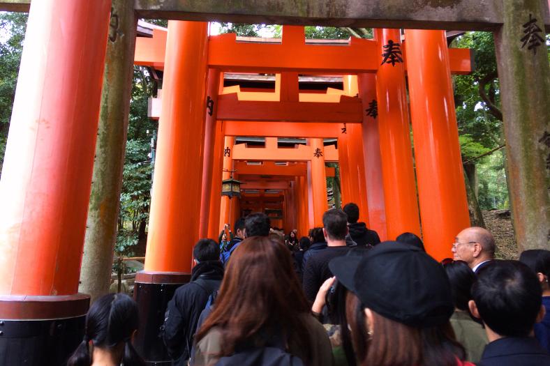 Oranžové brány a ľudia idúci ku svätyni Inari. Kjóto.