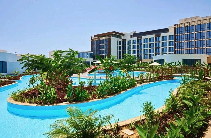 Bazén, záhrada a budova hotela Millennium Resort Salalah. Omán