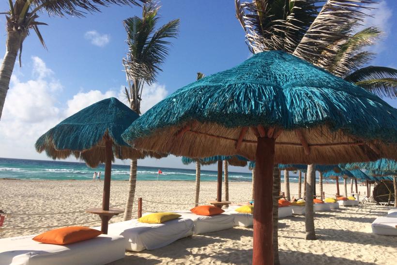 Piesková pláž s palmami a slnečníkmi v Cancune. Mexiko.