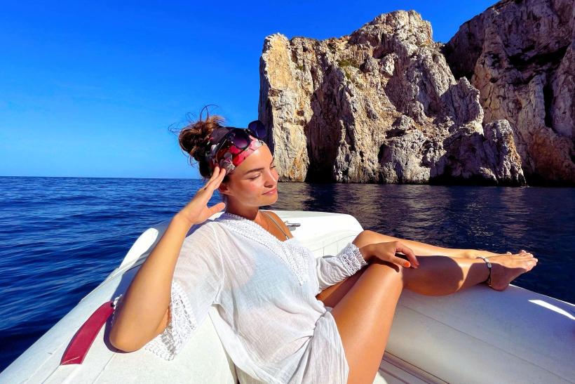 žena v bielych šatách na lodi počas plavby na Sardínii