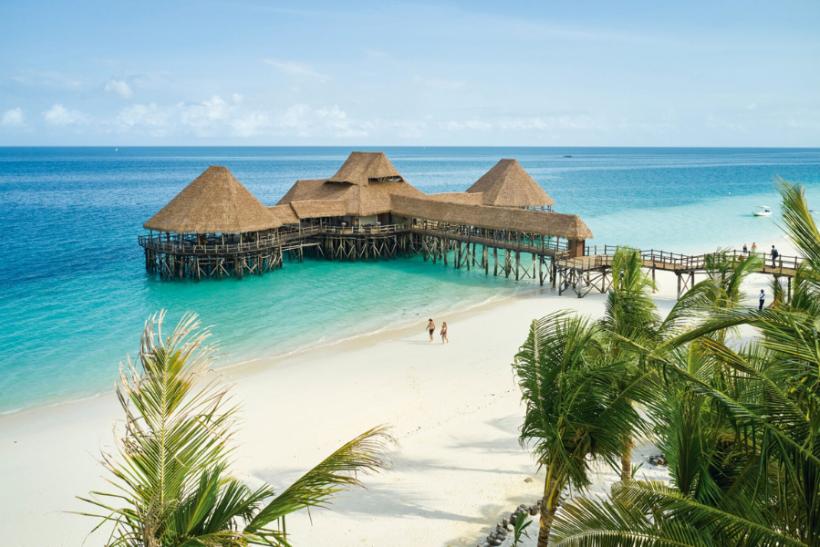 Exotická pláž s bielym pieskom, palmami a dreveným mólom. Zanzibar