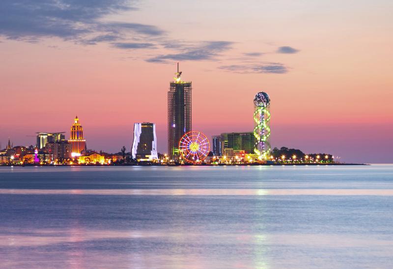 Vysvietené mesto Batumi s dovolenkovou atmosférou počas západu slnka.