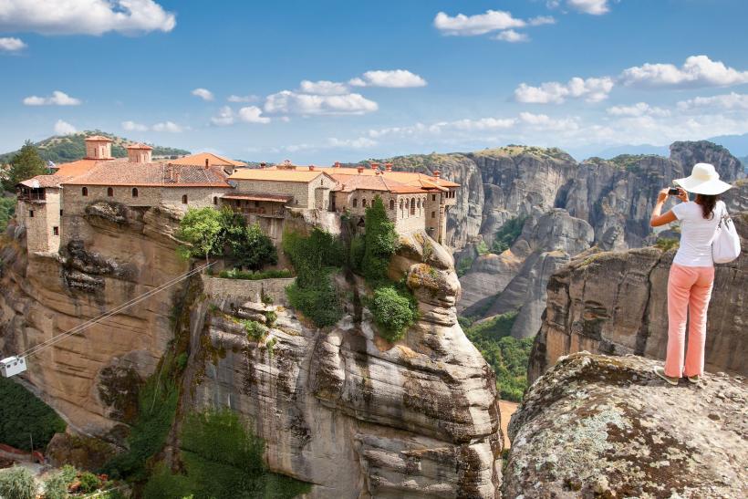 Žena v klobúku na vyhliadke na kláštor v časti Meteora v Grécku.