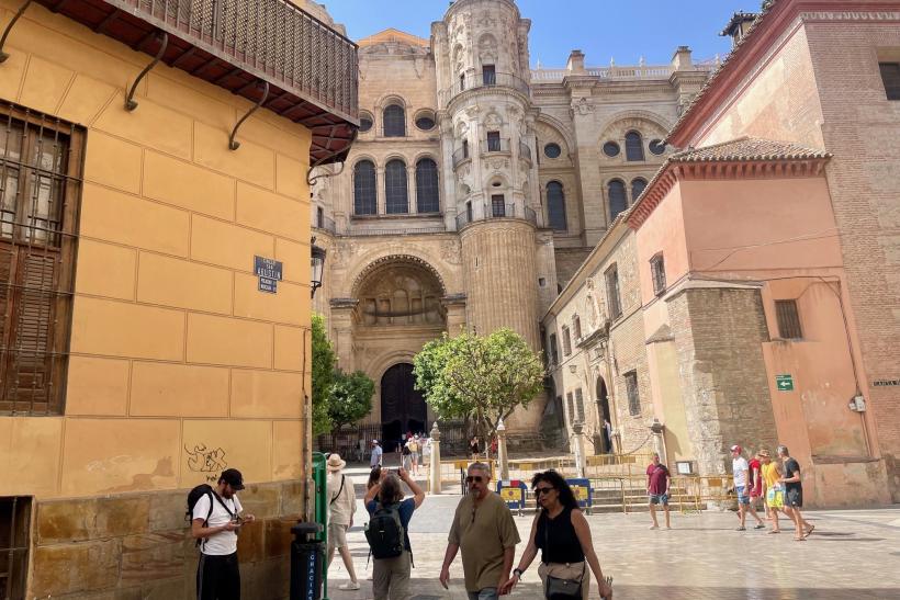 Katedrála medzi historickými domami v centre Malagy a turisti.