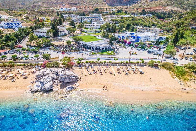 Piesková pláž a hotel s klientami na ostrove Rodos.