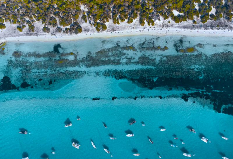 Pláž na ostrove Formentera a lode na mori.