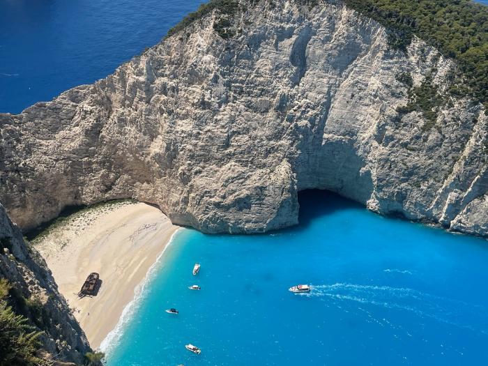 Pláž Navagio s vrakom lode a malými loďkami na mori v zálive.