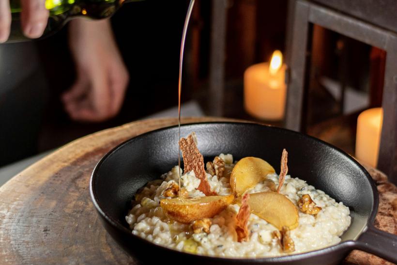 Muž polieva olivovým olejom risotto.