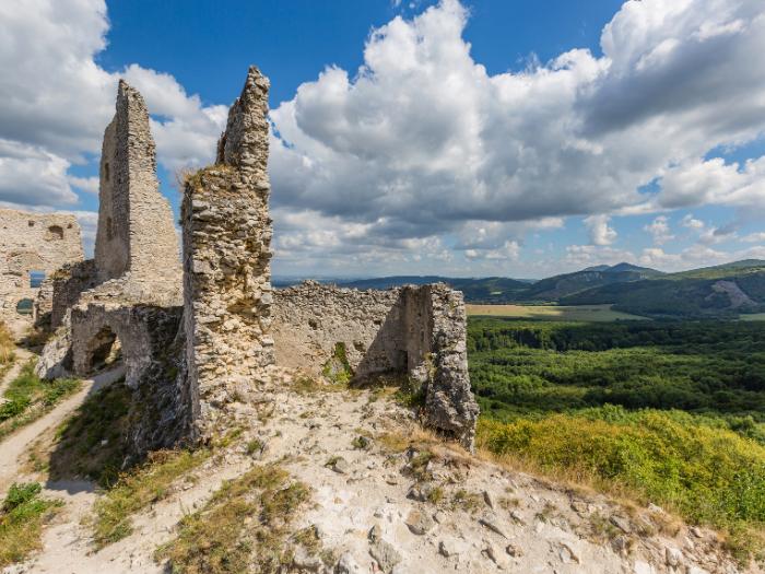 Zrúcaniny Plaveckého hradu a zelené kopce v pozadí počas dňa.
