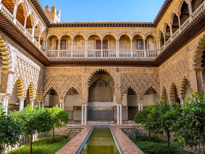 Alcazar v Seville s krásnym bazénom a zdobenými klenbami.