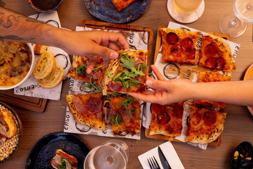Ľudia za stolom, kde je pizza.