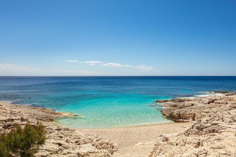 Tyrksové more a kamienková pláž na ostrove Lošinj.