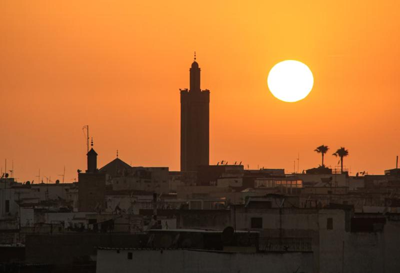 Západ slnka nad mestom Rabat s domami a mešitou.