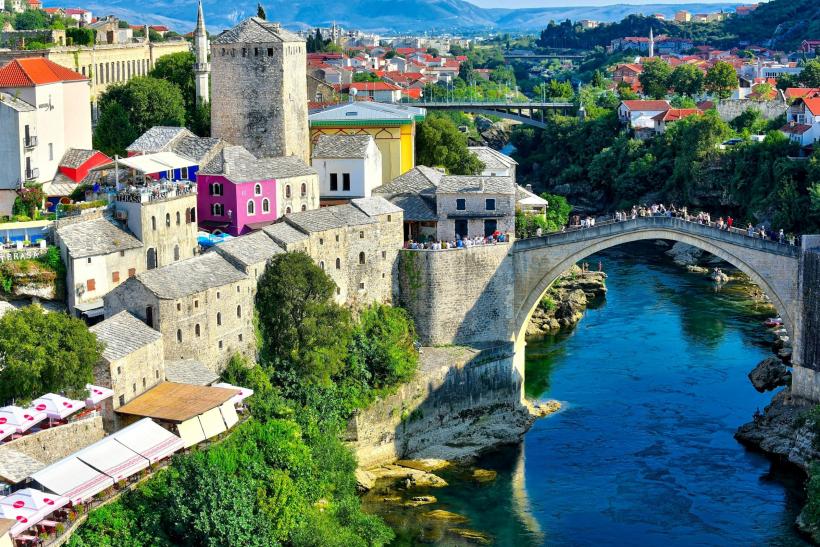 Mesto Mostar s kamenným mostom a domami a riekou.