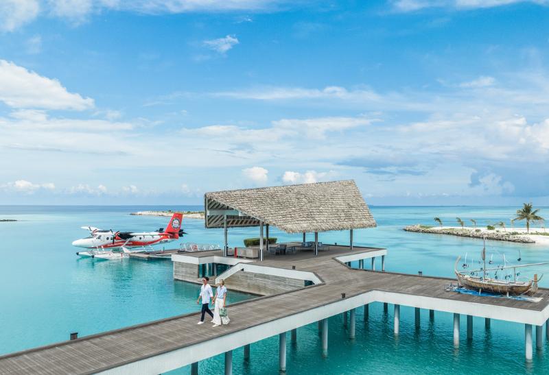 Pár kráčajúci po drevenom móle na Maldivách