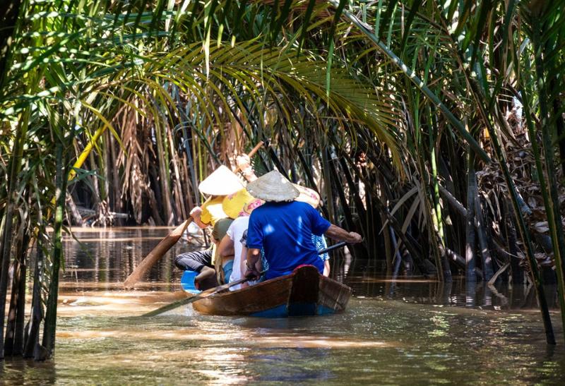 Ľudia plaviaci sa po rieke na člne vo Vietname.