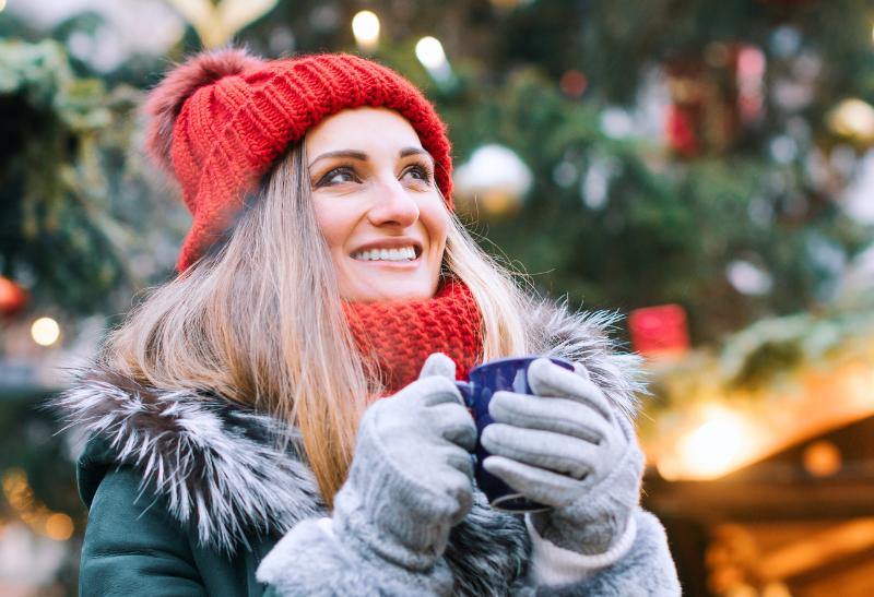 Žena na vianočných trhoch so šálkou v ruke.
