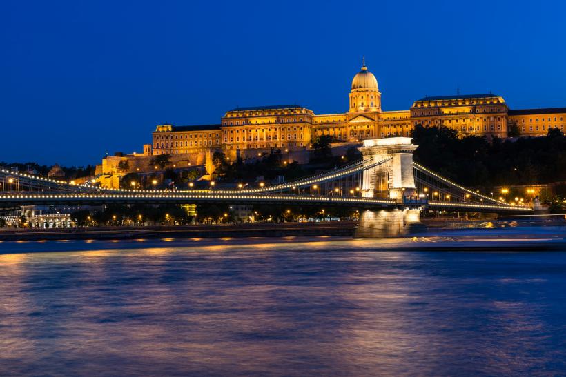 Večerné mesto Budapešť s mostom a historickými budovami.