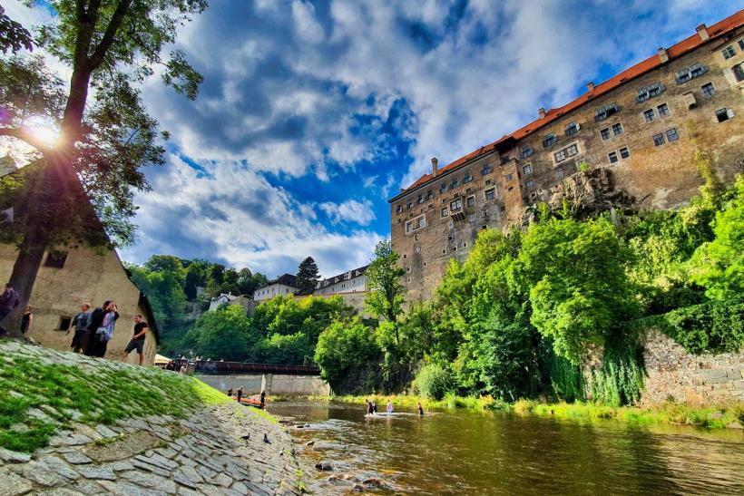 Turisti pri rieke pod hradom v meste Český Krumlov.