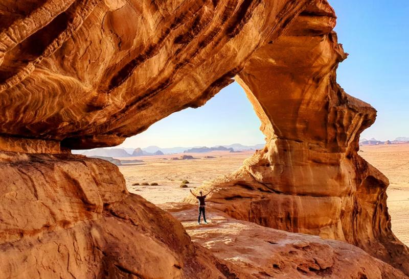 Muž stojaci na skalnom masíve v púšti Wadi Rum v Jordánsku.