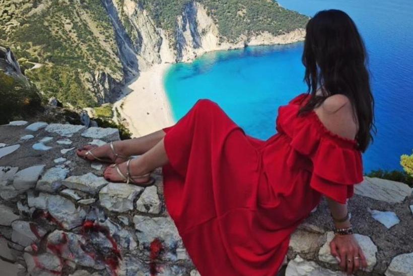 žena v červených šatách na vyhliadke Myrtos Beach, Kefalónia