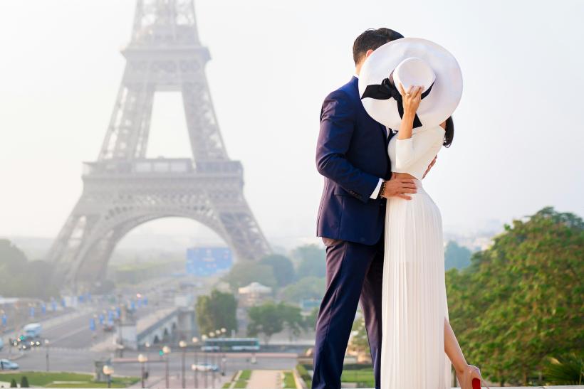 Bozkávajúci sa pár pred Eiffelovou vežou v Paríži.