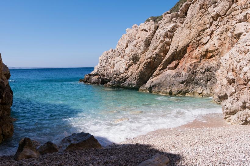 Skaly a krásna malá pláž na ostrove Karpathos.