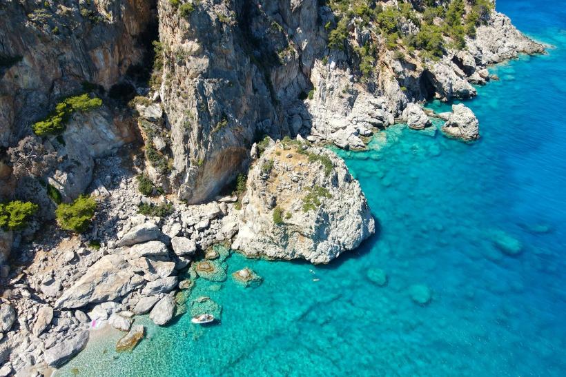 Skalný masív pri pobreží Karpathosu a malá loď.