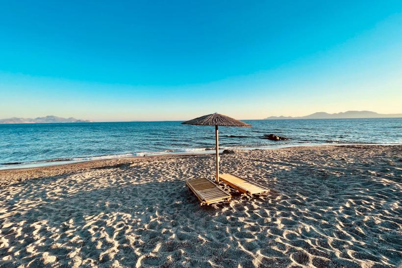 Piesková pláž a slnečník pri mori s výhľadom na pobrežie.