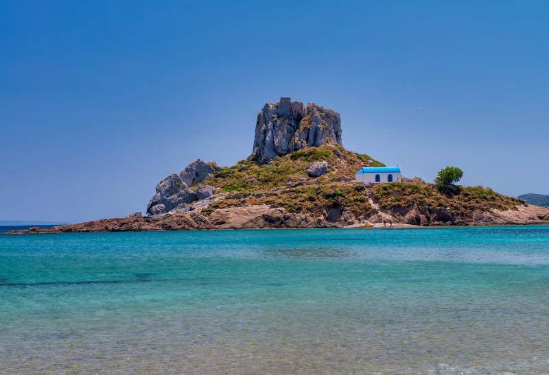 Ostrovček Kastri s malým kostolíkom a blankytné more na pláži Agios Stefanos.