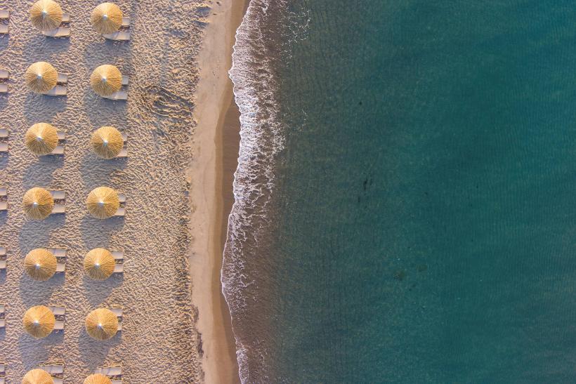 Piesková pláž, tyrkysové more a slnečníky na ostrove Kos.