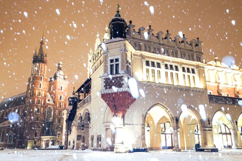 Zasnežené námestie s historickými budovami v Krakove. Poľsko