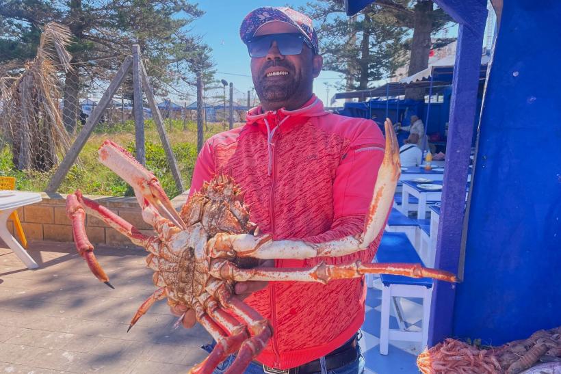 Maročan so živým krabom na trhu pri mori v Maroku.