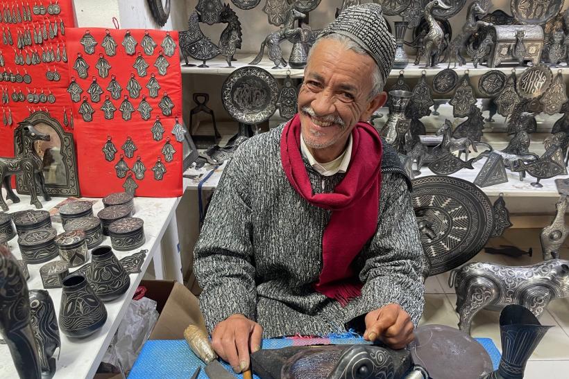 Usmiaty Maročna pri výrobe tepaných výrobkov v jeho dielni v Meknes.