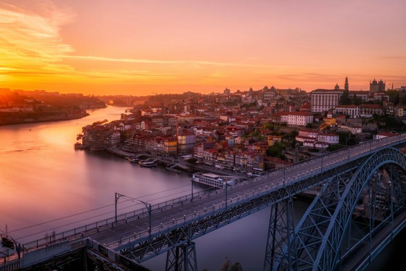 Želzený most nad riekou Douro a mesto Porto pri západe slnka.