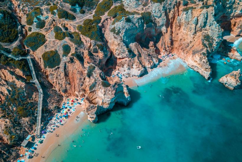 Skalné pobrežie Algarve a ľudia na pláži.