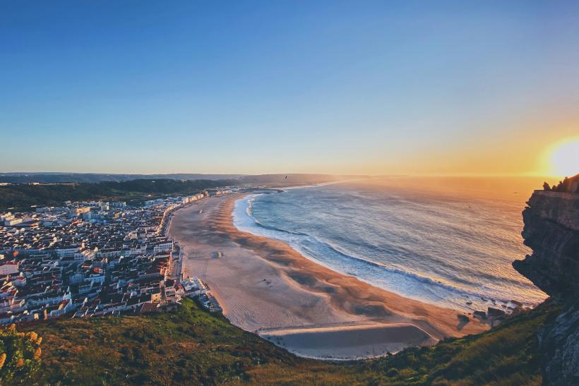 Mesto Nazaré, pláž, oceána a západ slnka.